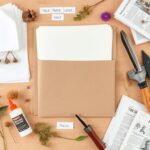 Materiały potrzebne do zrobienia zielnika, w tym kartki, teczka, klej, etykiety i narzędzia do zbierania roślin