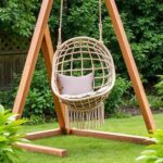 Fotel wiszący na stojaku w ogrodzie, zapewniający miejsce do relaksu